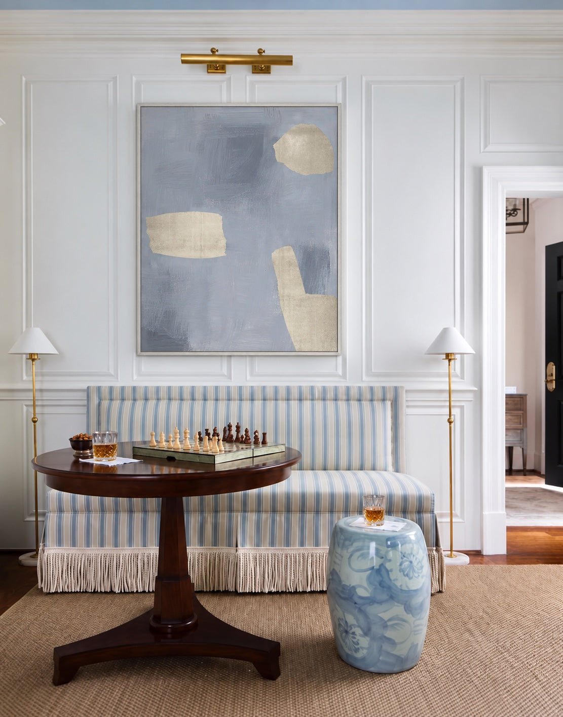 Lulled to Sleep 4 above a blue-striped bench beneath a brass picture light